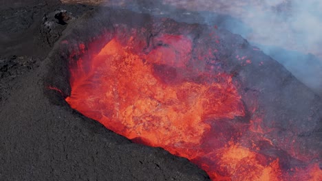 Fiery-magma-bubbling-in-volcano-crater-hole-of-Litli-Hrútur,-aerial