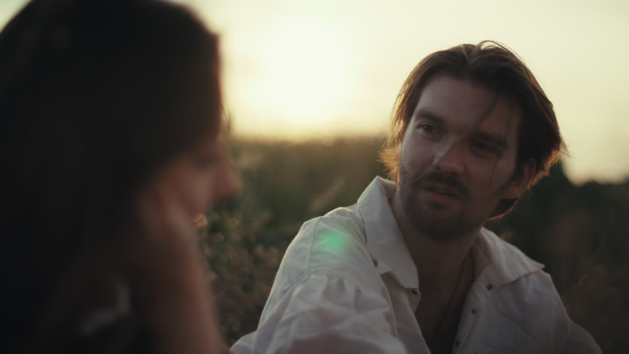 Couple having a romantic conversation at sunset in a field
