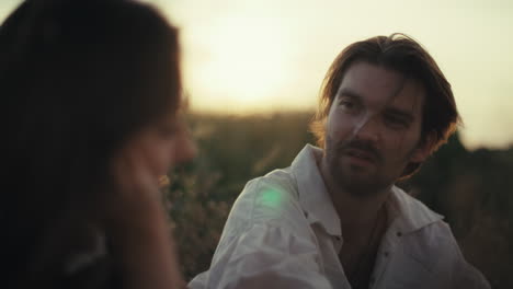 couple having a romantic conversation at sunset in a field