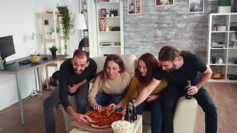 grupo de amigos inclinándose para tomar una rebanada de pizza