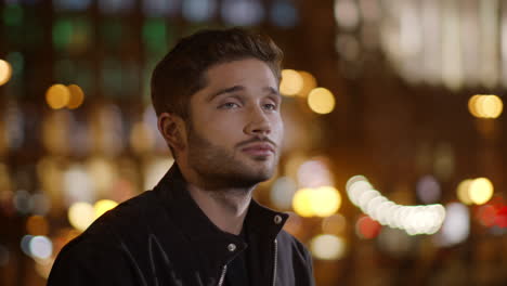 Handsome-hipster-guy-standing-on-dark-street.-Serious-man-looking-around-outside