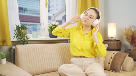 young woman looking out the window and listening to music with headphones.