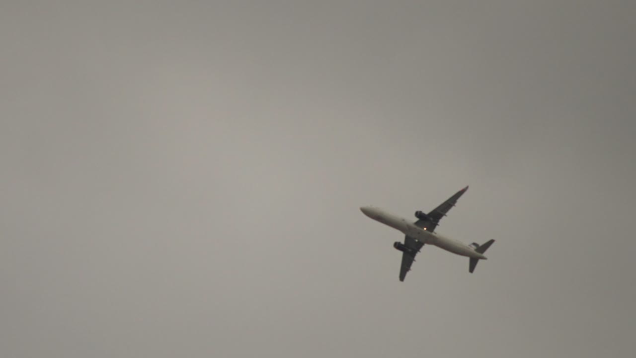 SLOWMOTION: SPORINGSOPTAGELSE AF ET A321-FLY, DER FLYVER OVER PÅ EN OVERSKYET DAG