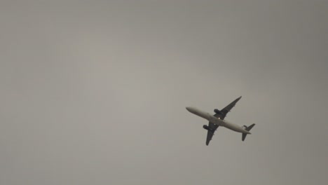 slow motion: tracking shot of an a321 plane flying over at a cloudy day