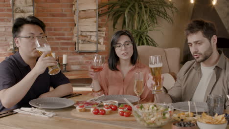 a group of three friends toast with their glasses at a dinner party. multiracial friends reunion.