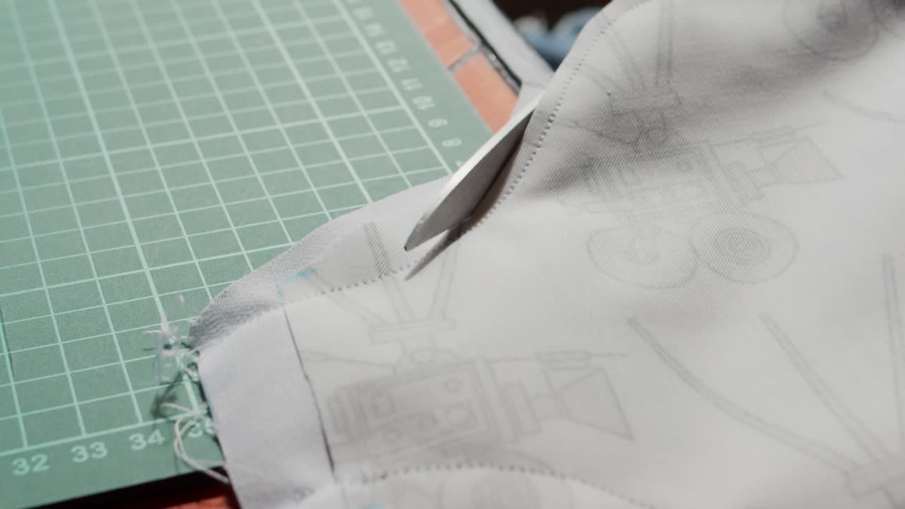 tijeras cortadas cerca de un borde cosido de tela impresa sobre un fondo de tablero de corte