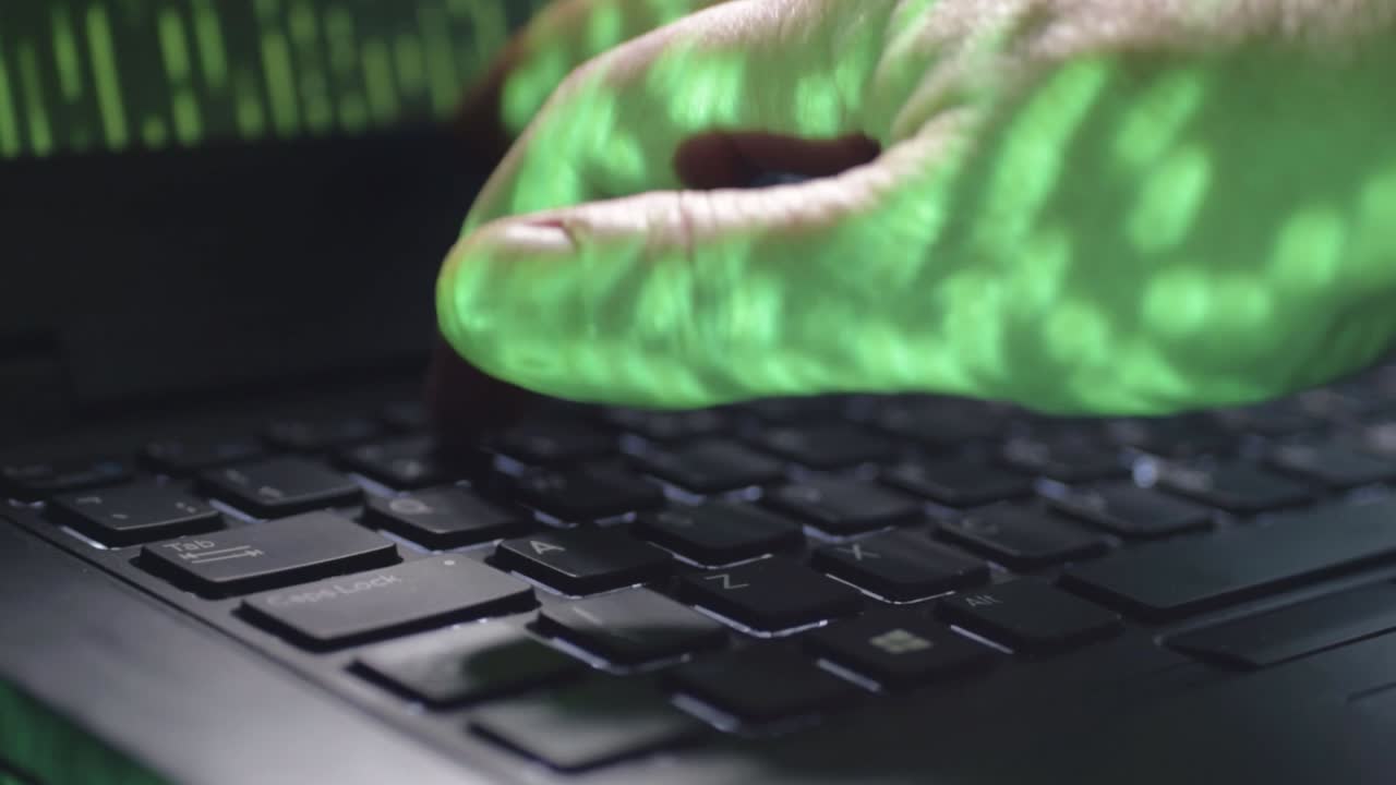 Coder typing on laptop with green code close up shot