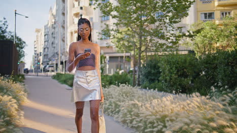 fashion model strolling alley alone. brunette lady typing phone message