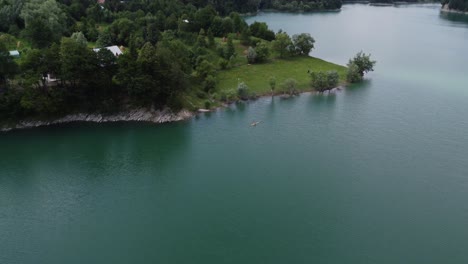 Aerial-backwards-moving-shot-of-the-natural-landscape-of-the-turquoise-lake-of-Paltinu-at-sunset-in-Doftana-Valley-Romania