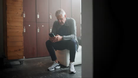 man using phone in locker room