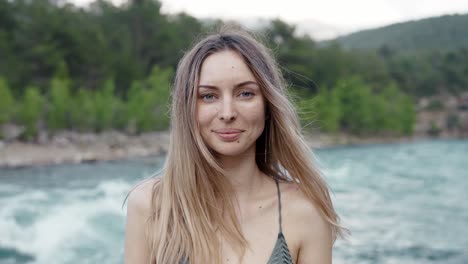 carefree woman standing in front camera - green hills and river on background