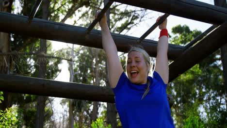 mujer decidida haciendo ejercicio en una barra de mono durante una carrera de obstáculos