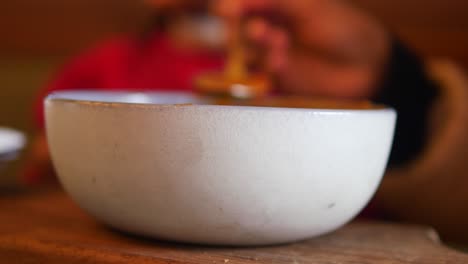 person eating soup from a white bowl