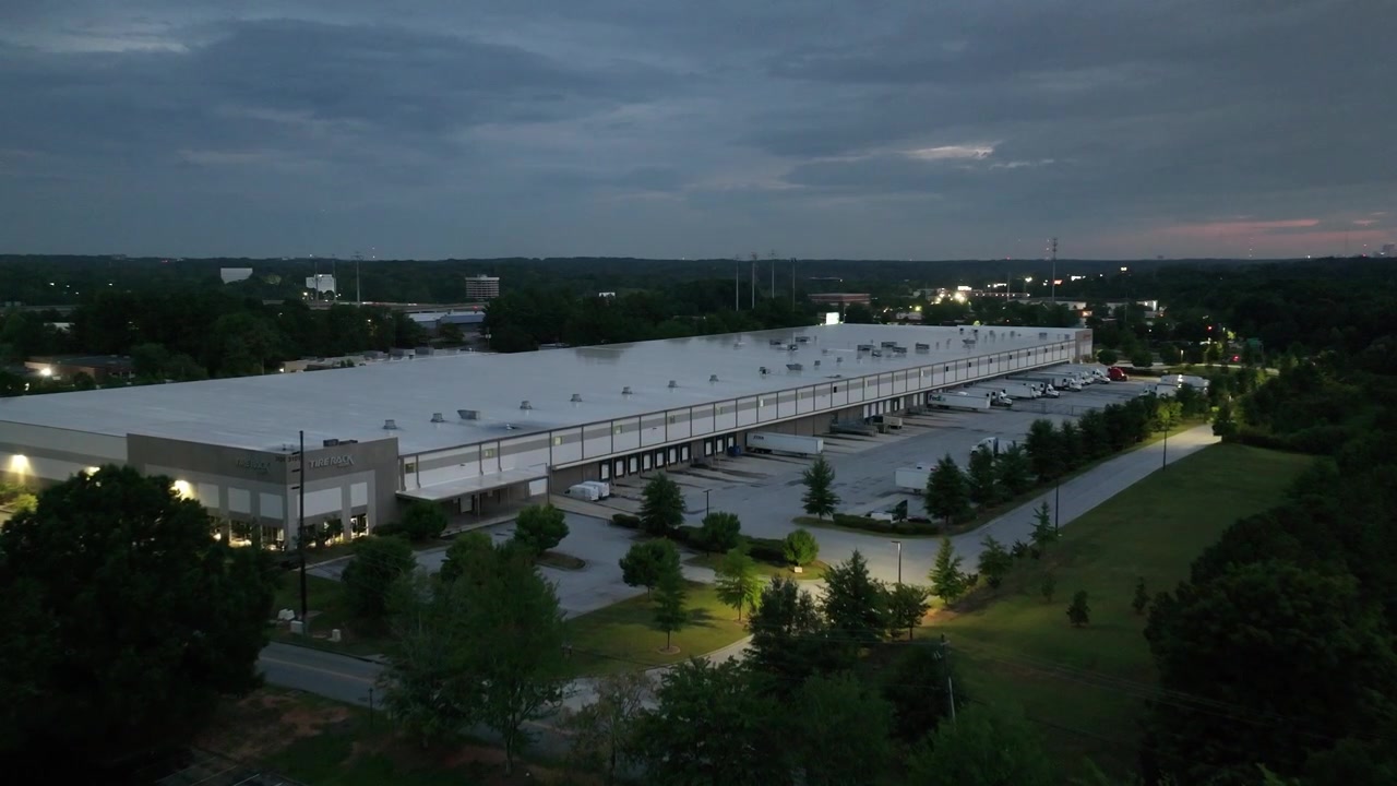 Aerial view of tire shop warehouse facility with heavy duty trucks parked at parking lot near Interstate 285 at night, Doraville, Atlanta, USA