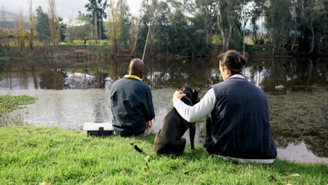 fishing, friends and men with dog at a lake rear