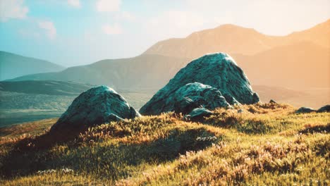 Pradera-Con-Enormes-Piedras-Entre-La-Hierba-En-La-Ladera-Al-Atardecer