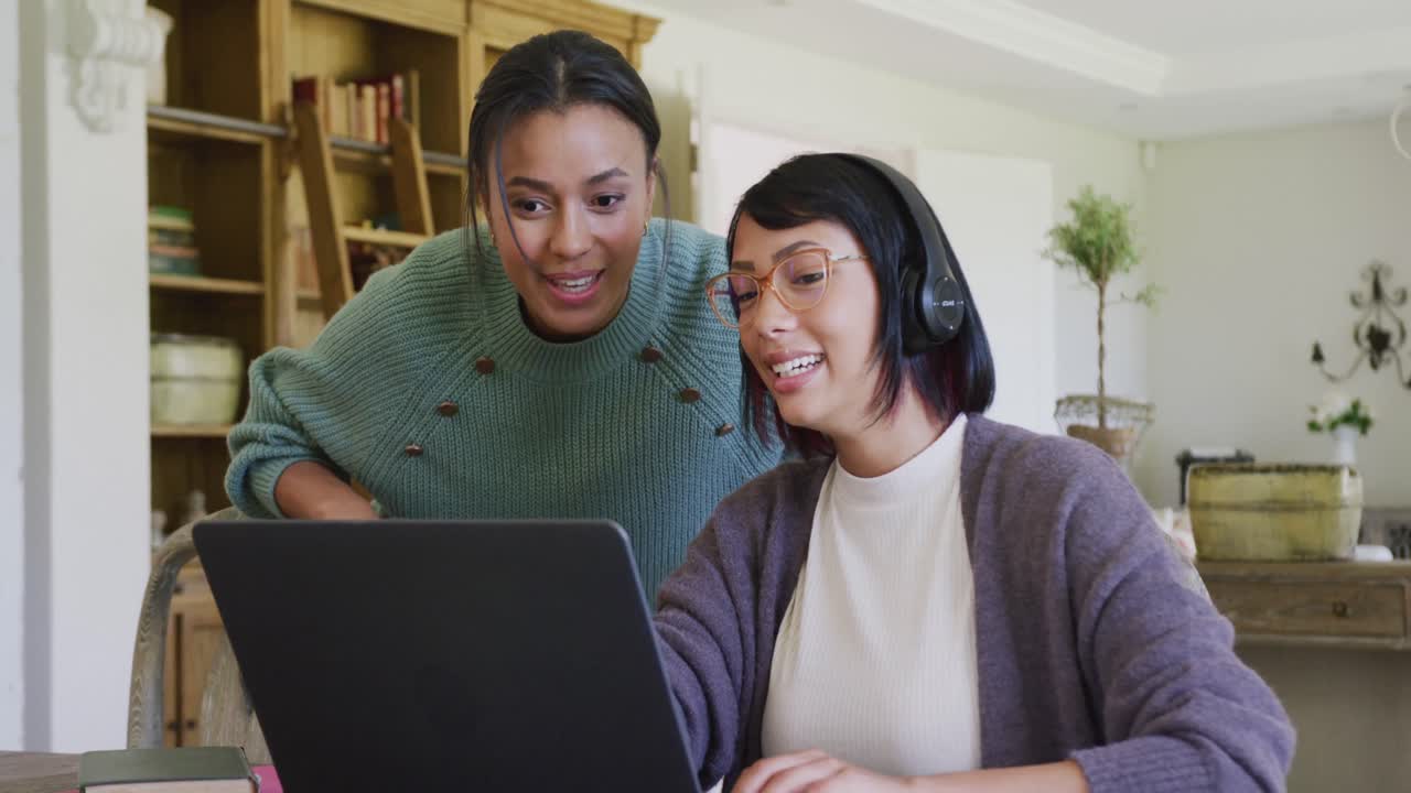 hermanas bi-raciales felices usando una computadora portátil, en cámara lenta.