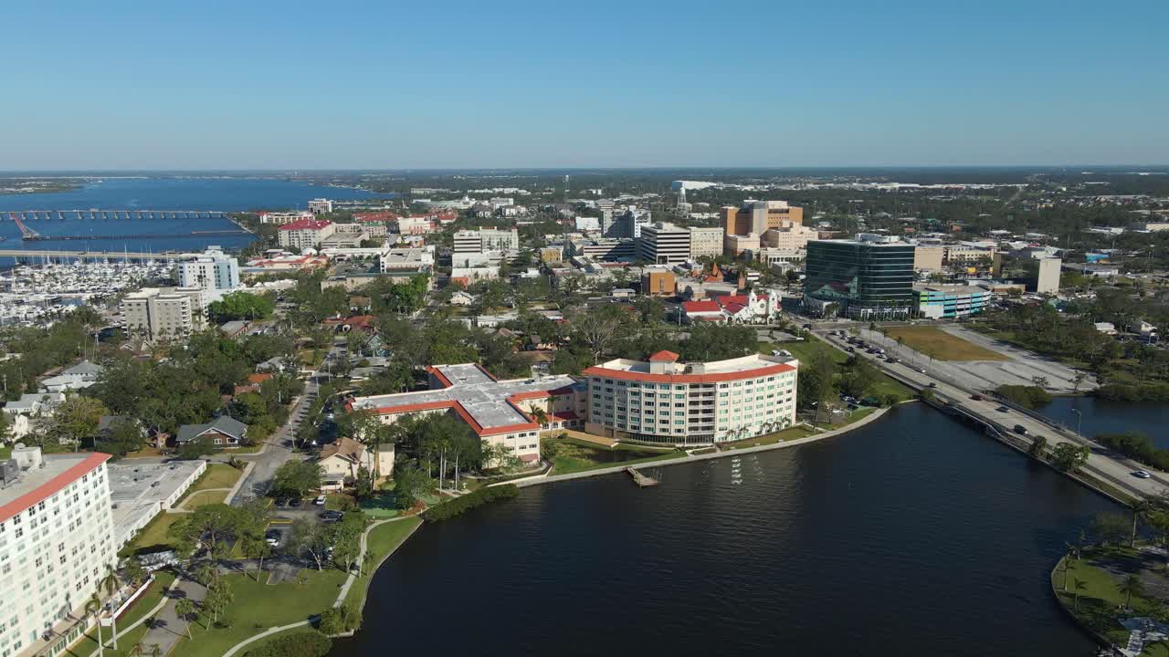 Aerial drone footage of Bradenton Florida showcasing the downtown skyline, riverfront, and bridges under clear blue skies. Wide Crane Down Left E