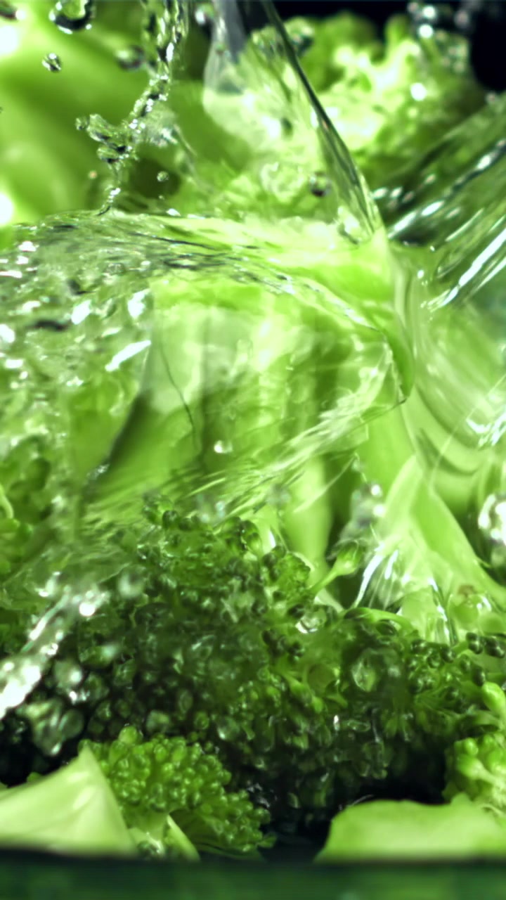 Cimette di broccoli freschi e verdi che vengono sciacquate con acqua.