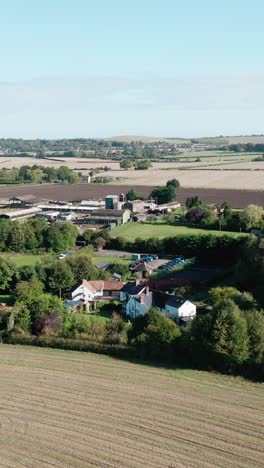 drone flies downward above fields in english countryside with visible hedgerows and plots