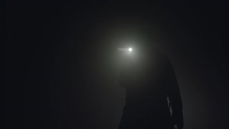 person with flashlight in dark environment