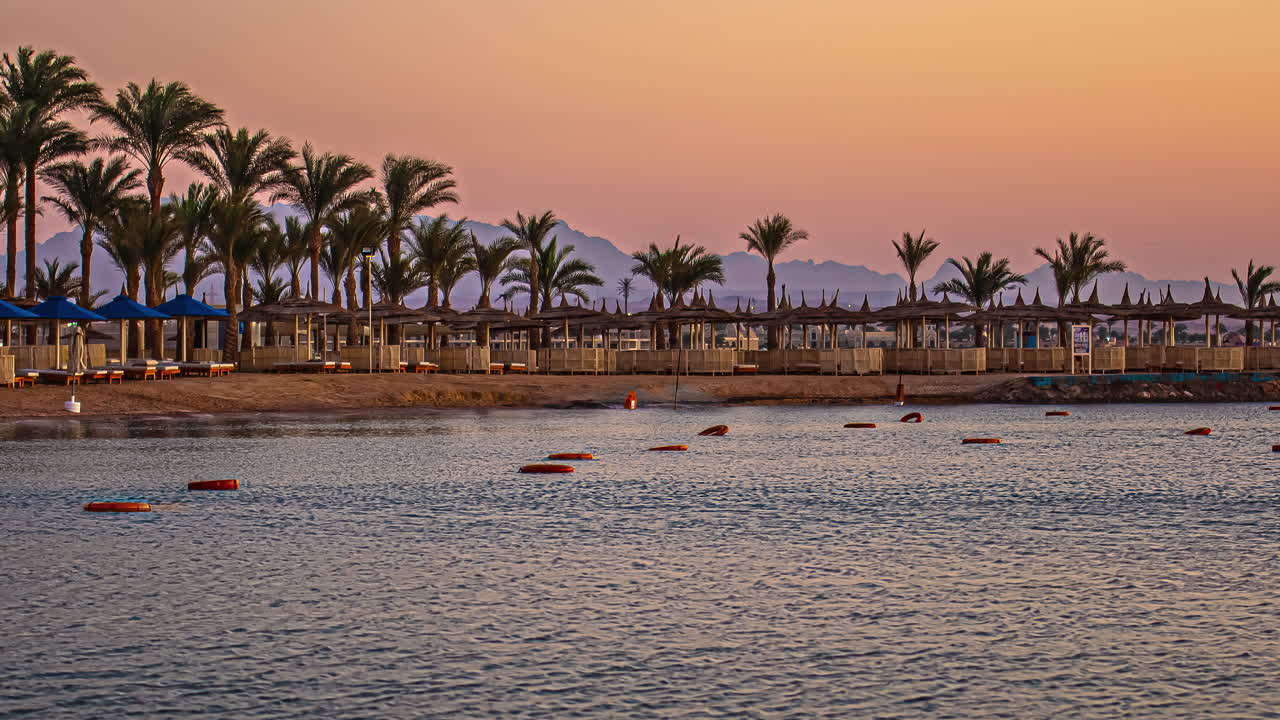 Timelapse dal giorno all'alba in una baia con palme e montagne, Hurghada, Egitto.
