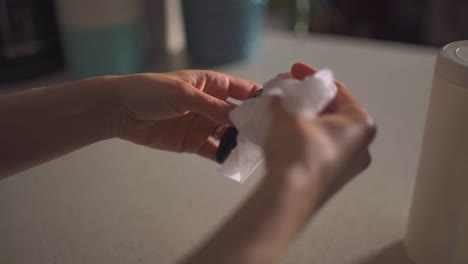 close up of woman's hands wiping down car keys with disinfectant wipe