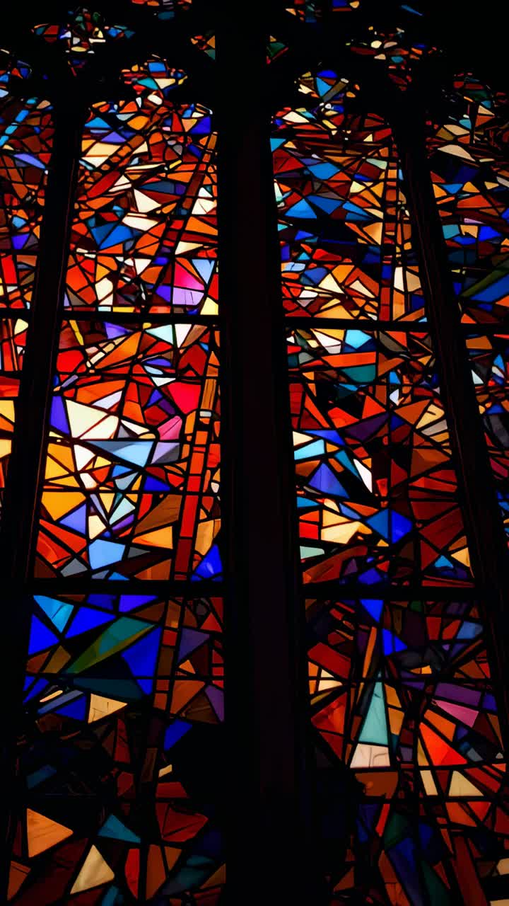 Vertical video: Sunlight shifting, lighting stained glass in chapel, showing lead lines, dark shape