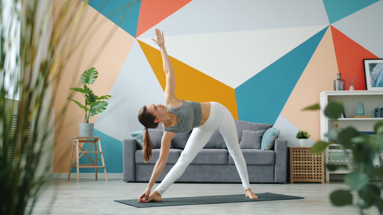 mujer practicando posturas de yoga en casa