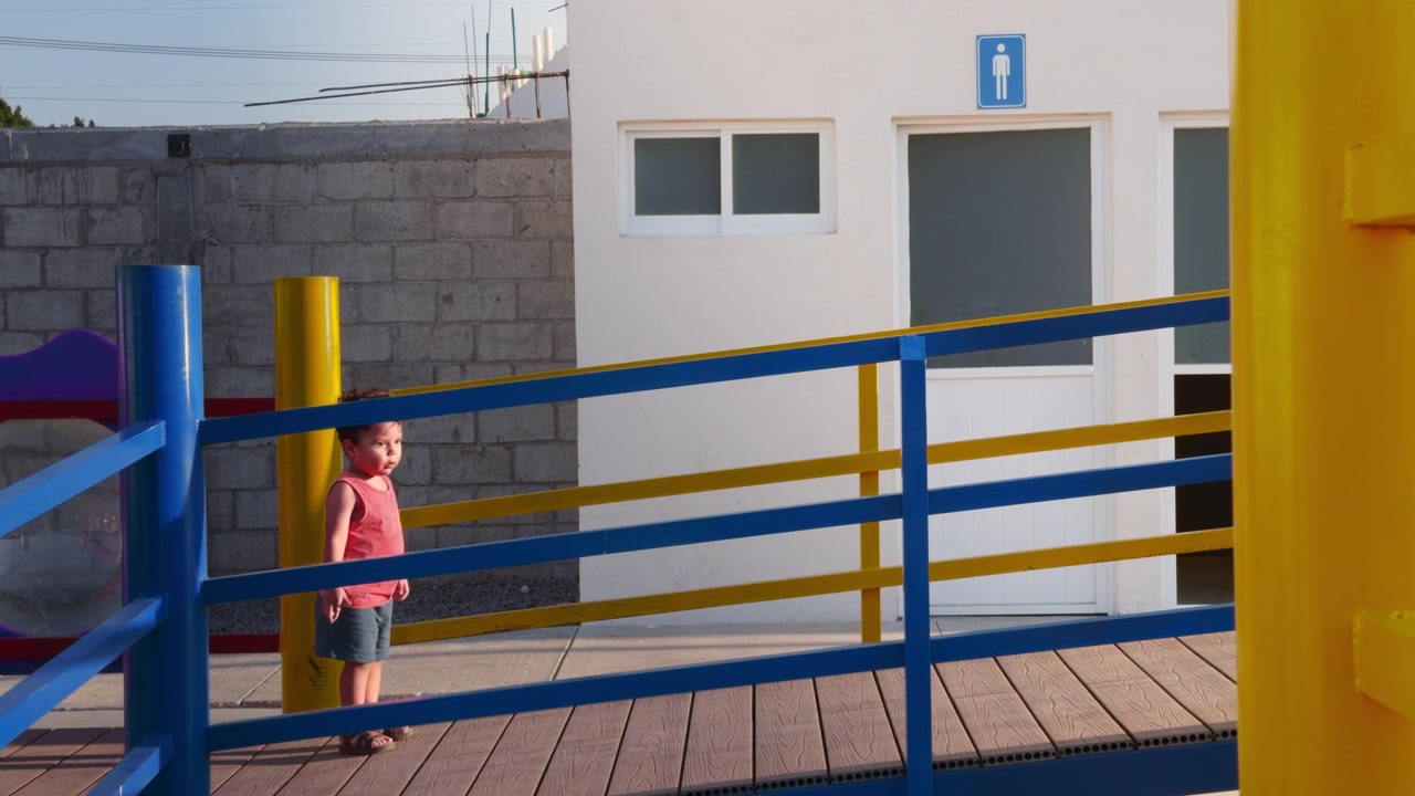 Niño pequeño caucásico inteligente corriendo por una pendiente en un parque infantil al aire libre, vistiendo ropa casual brillante en un día soleado para un concepto comercial saludable