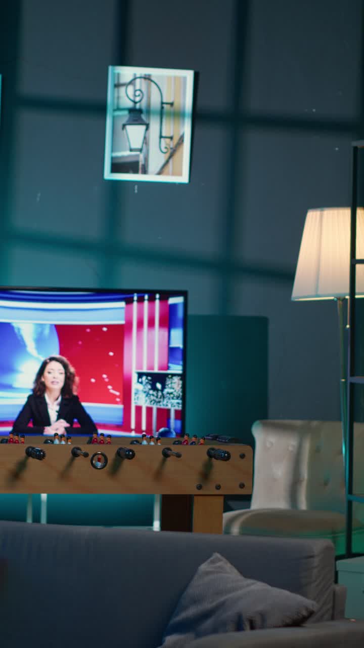Salón vacío con futbolín y televisión reproduciendo noticias