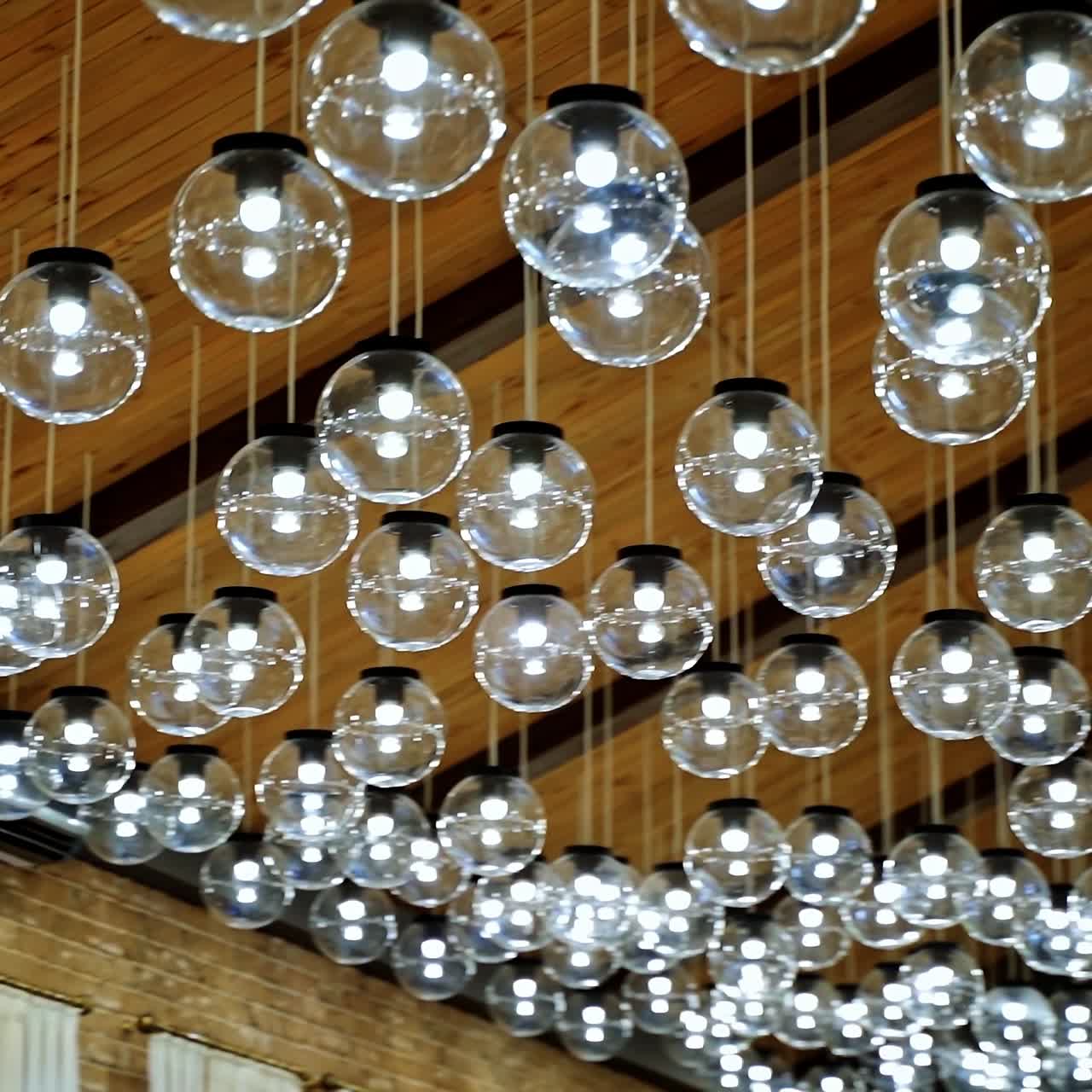Round transparent bulbs hanging from wooden celling. View from below. Modern interior. Modern light classic lamp hanging from celling. Vintage lamps, bulb lamps. Video from below.