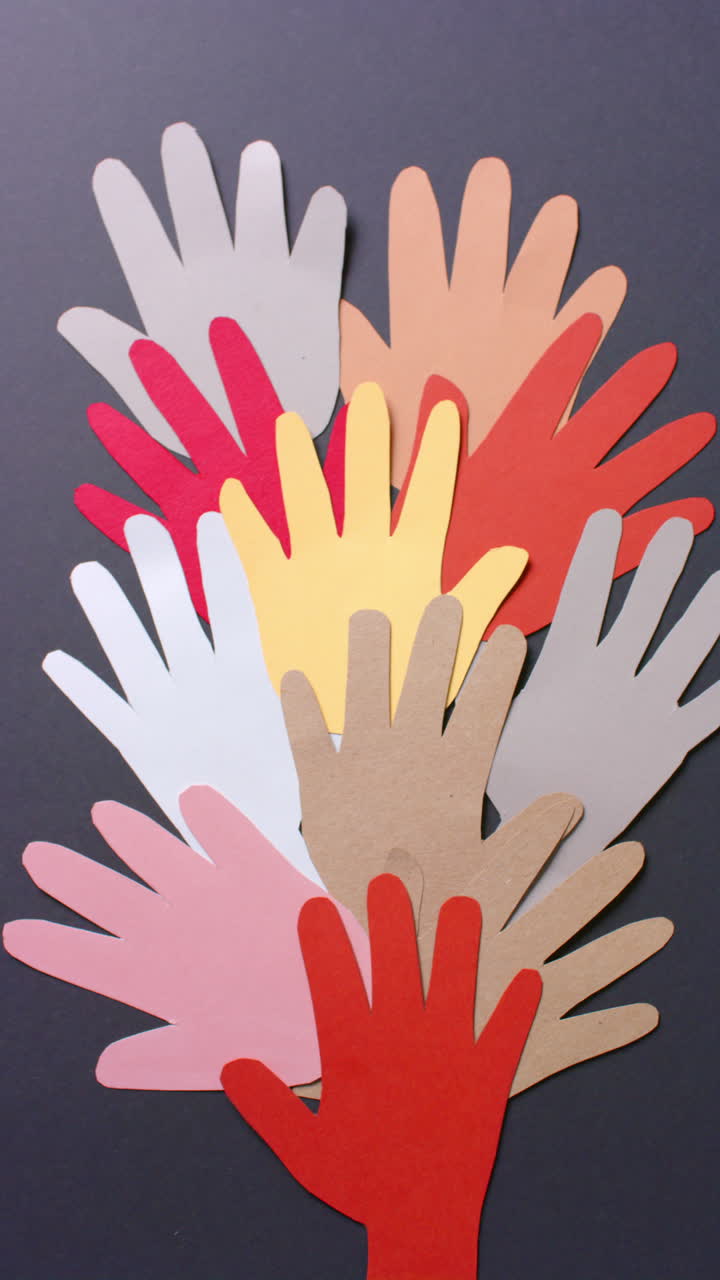 Vertical video of hands together made of colourful paper on gray background with copy space