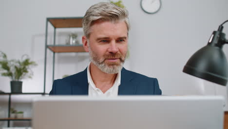 Close-up businessman freelancer at office workplace working on laptop computer sends online messages
