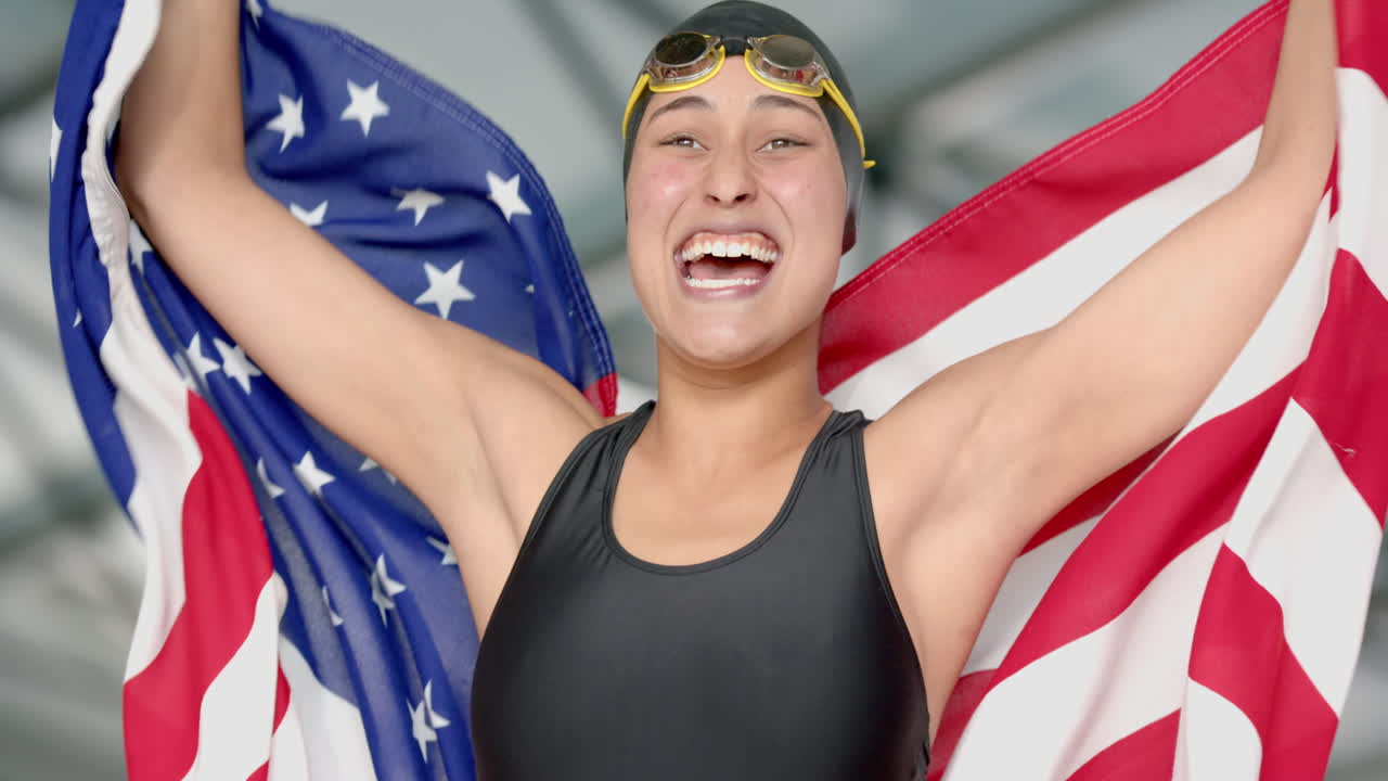 Celebrating victory, female swimmer holding American flag with arms raised, smiling broadly