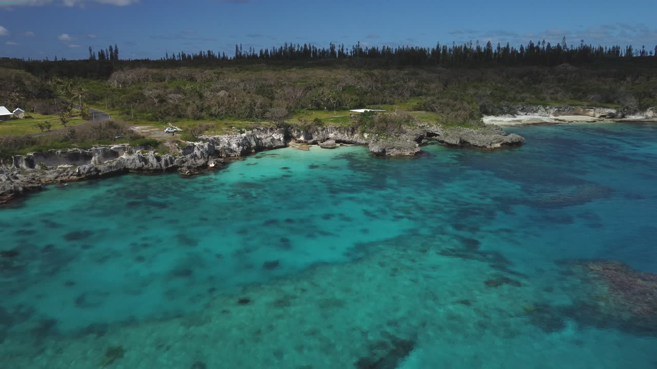 Aerial view over blue water, shoreline of Loyalty islands - reverse, drone shot
