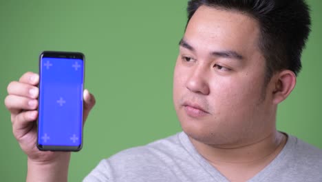 초록색 배경에 젊은 잘생긴 과체중 아시아인