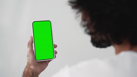 young man touch screen smartphone with green chroma key close-up. guy tapping gesture on mobile phone mock-up. concept watch and show internet social media, calls, read news, app, iot, e-shopping 4k