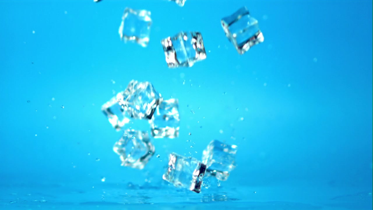 IJsblokjes vallen en spatten op een blauw oppervlak in slow motion