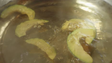 close up of pumpkin dropped into the boiling soup pot. vegetarian concept. sukiyaki or shabu