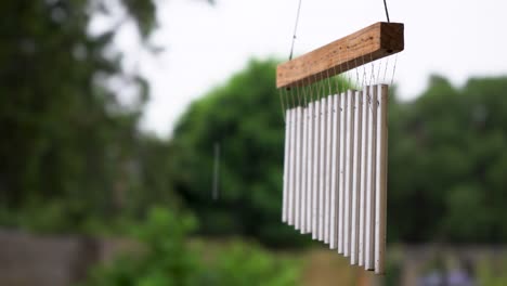 close up of metal tubes wind chime hanging on a rainy day, selective focus