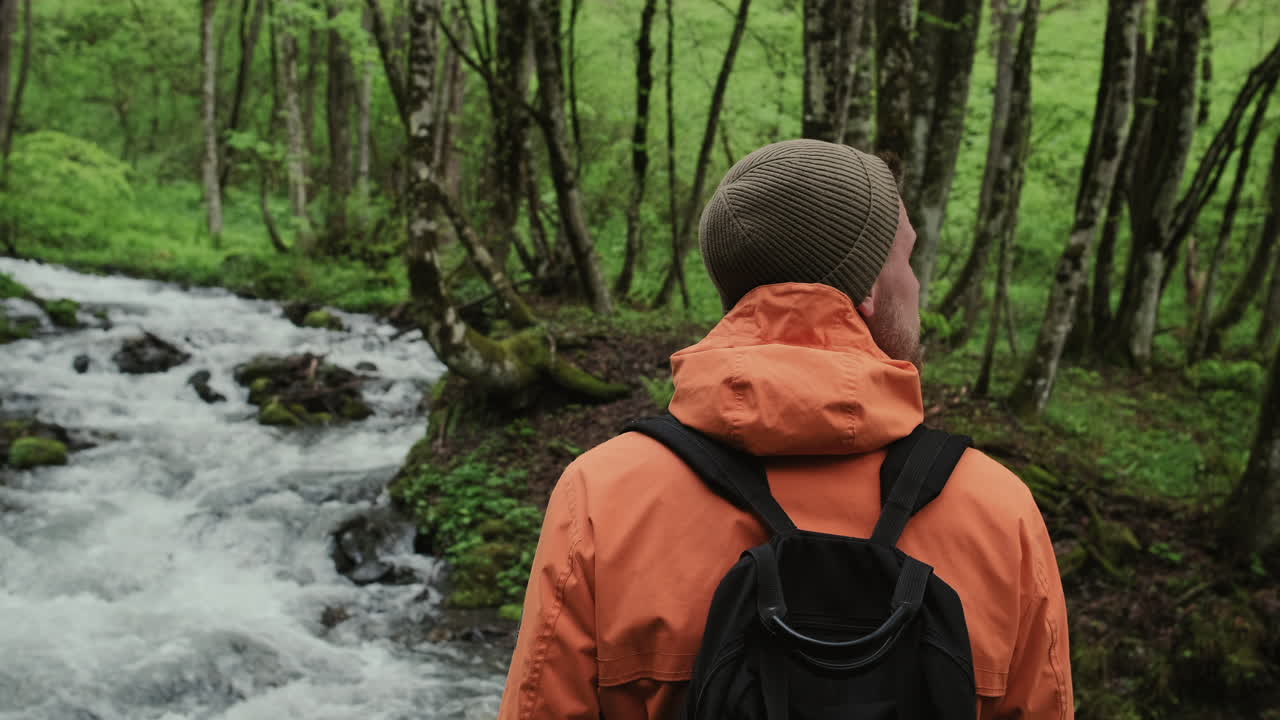 hombre caminando en un arroyo del bosque
