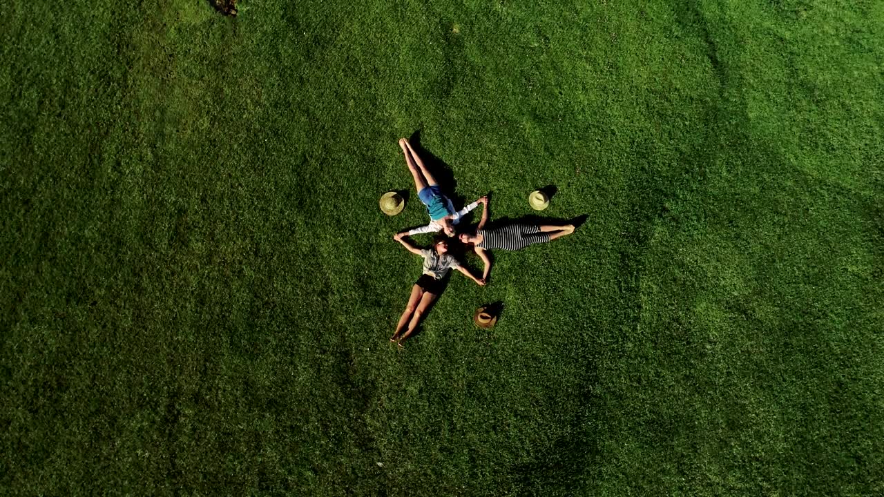 초록 잔디 위에 누워있는 세 명의 매력적인 소녀들이 잔디에서 즐거움을 즐기고 있습니다.