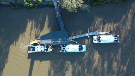 Disparo-De-Dron-De-Arriba-Hacia-Abajo-Del-Barco-De-Gato-De-La-Ciudad-Que-Sale-Del-Muelle-Y-Se-Aleja-En-El-Río