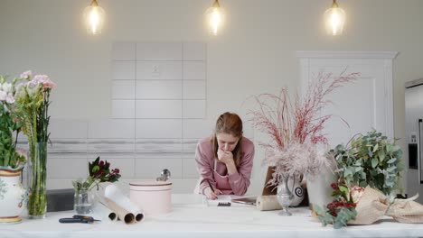 the girl florist in the shop after a working day counts on the calculator expenses for a month sadly understands that there is a crisis and there are no sales