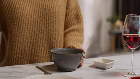 close up de una mujer en casa en la cocina preparando una comida saludable vegetariana o vegana comiendo un plato de ensalada tabbouleh con un vaso de vino