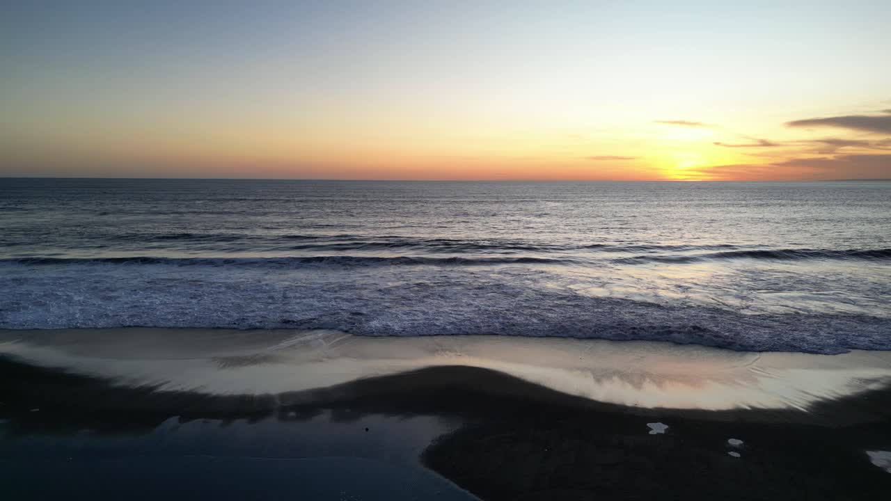 una hermosa puesta de sol en el sur de bali mirando a través del vasto paisaje marítimo con un árbol de coco en primer plano, aérea
