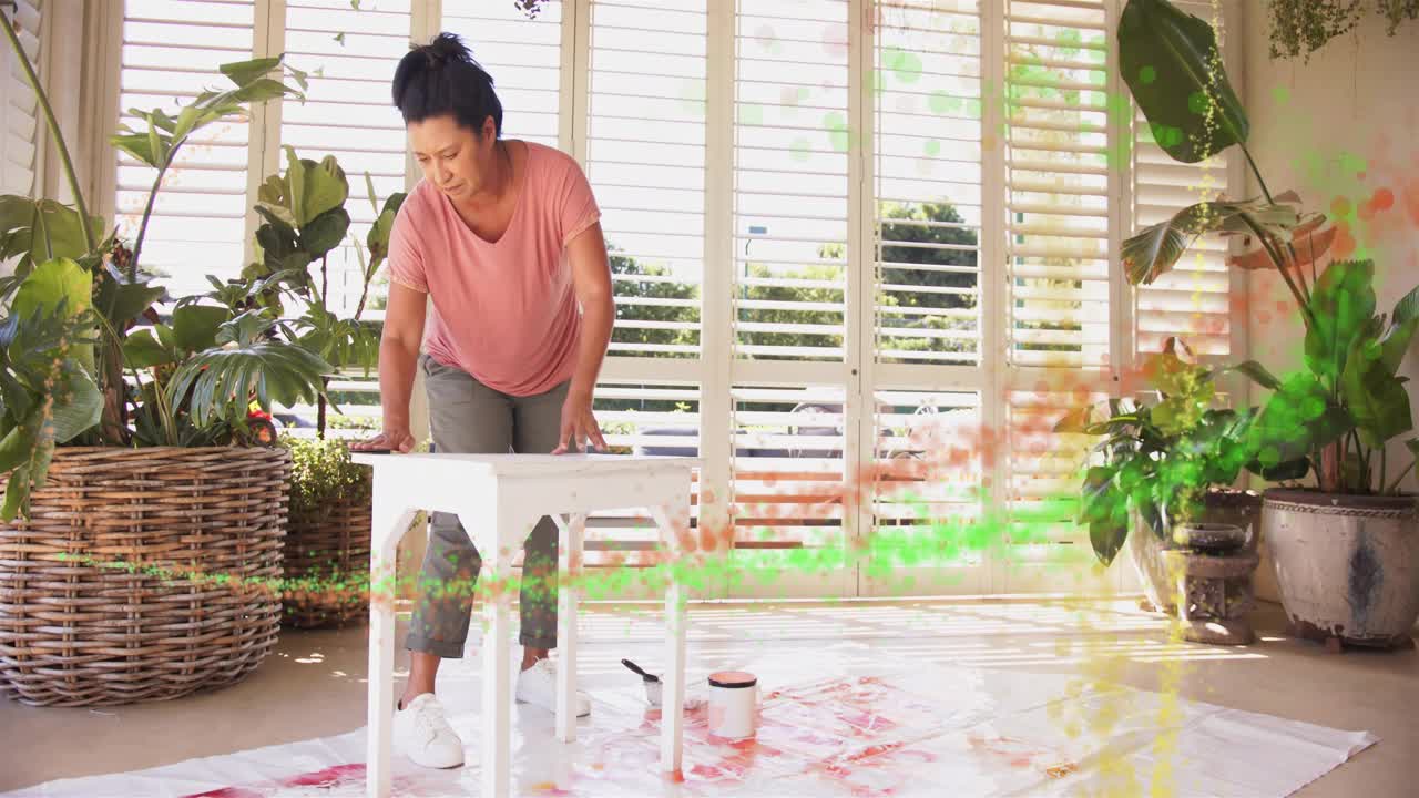 Woman pressing tabletop, wiping and sanding white table for home decor, colored swirls intersecting