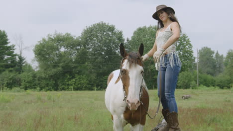 cowgirl mounting her adult pinto horse in a field-1