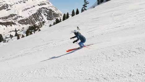 female ski expert showing beautiful ski turns on a steep ski slope in beautiful mountain panorama